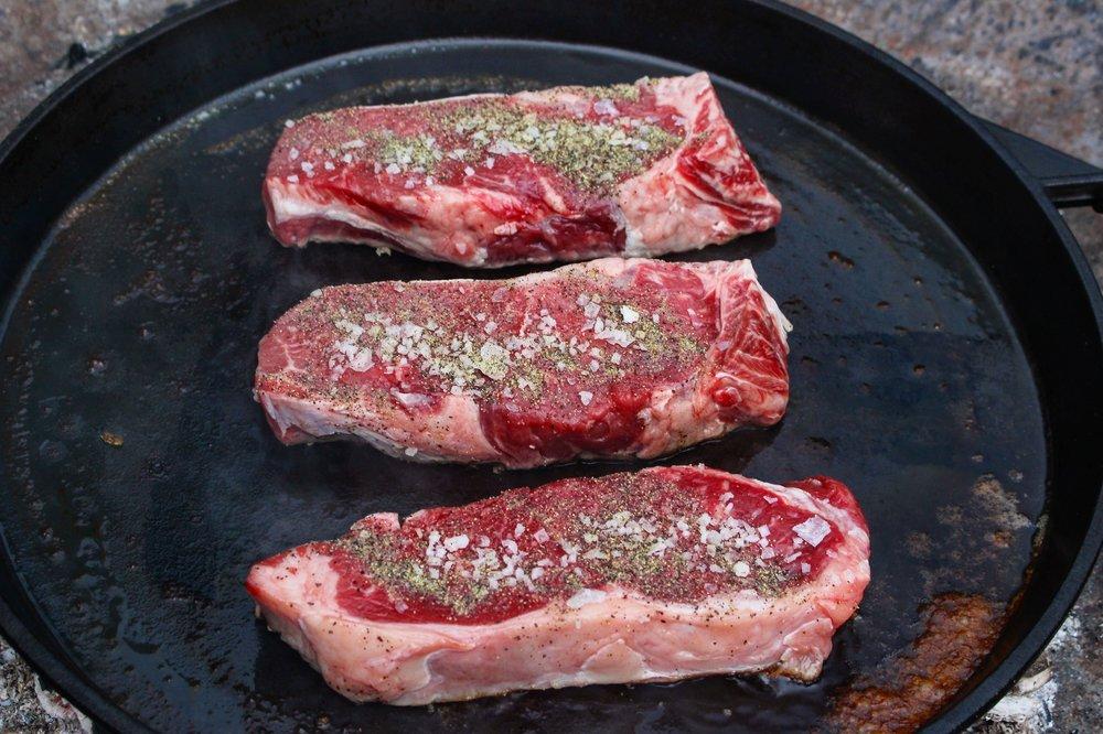  Seasoned steaks being cooked