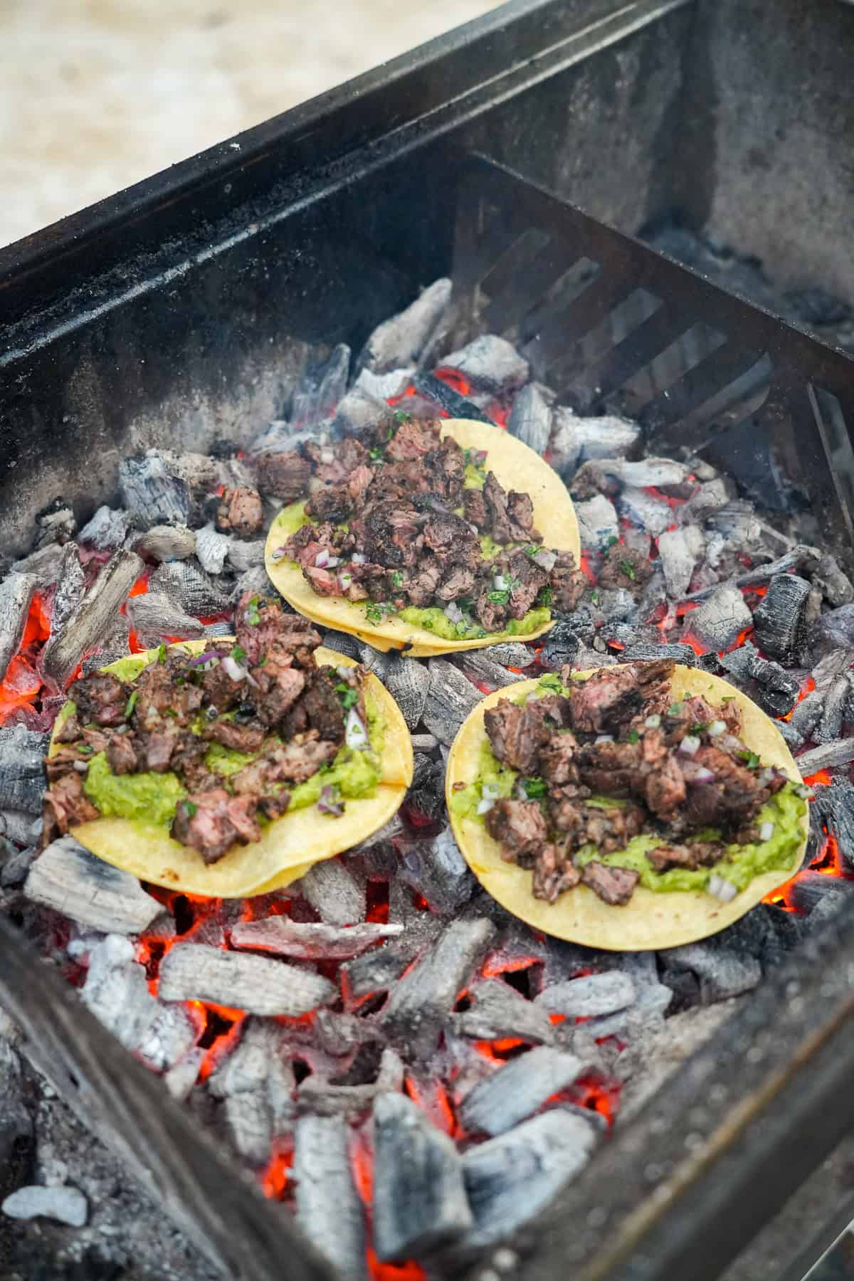 Skirt steak tacos assembled on tortillas, then laid directly on top of the charcoal in the grill