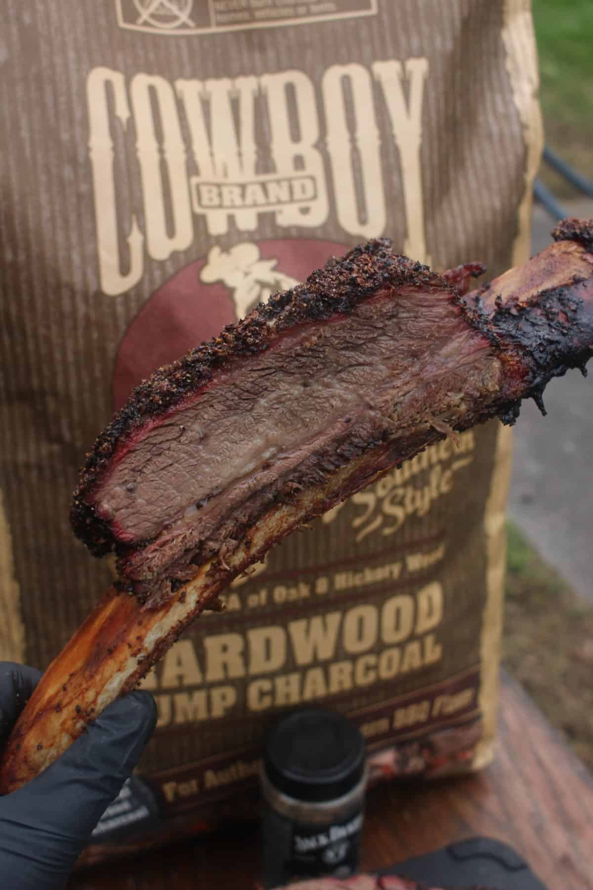 A sliced Smoked Jack Daniels Beef Ribs sliced and being held by the bone. 