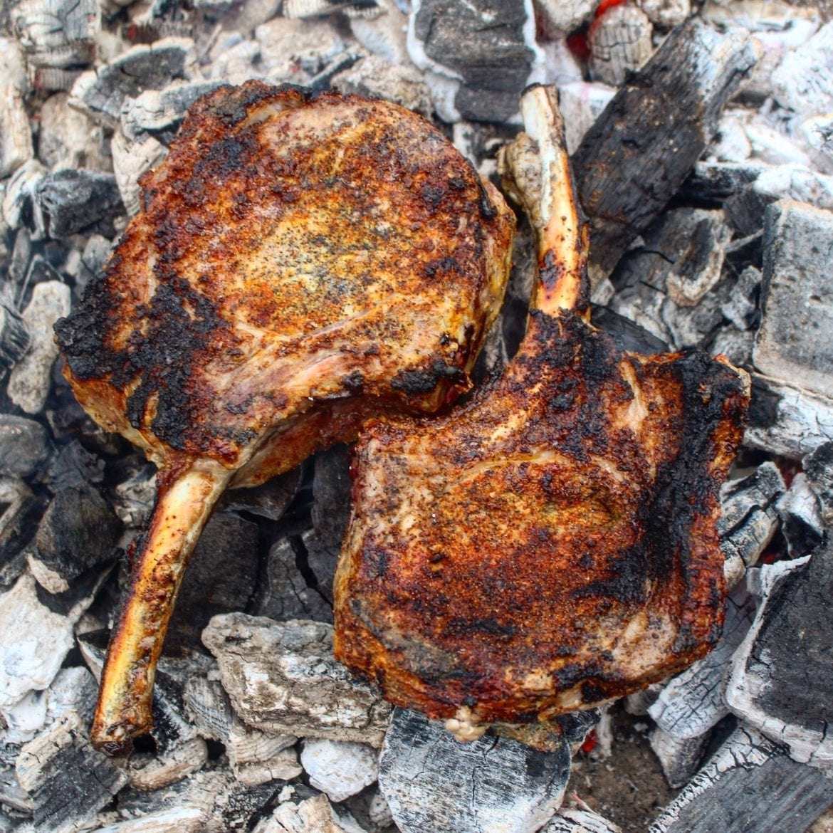 Tomahawk pork chops laying on top of the bed of coals.