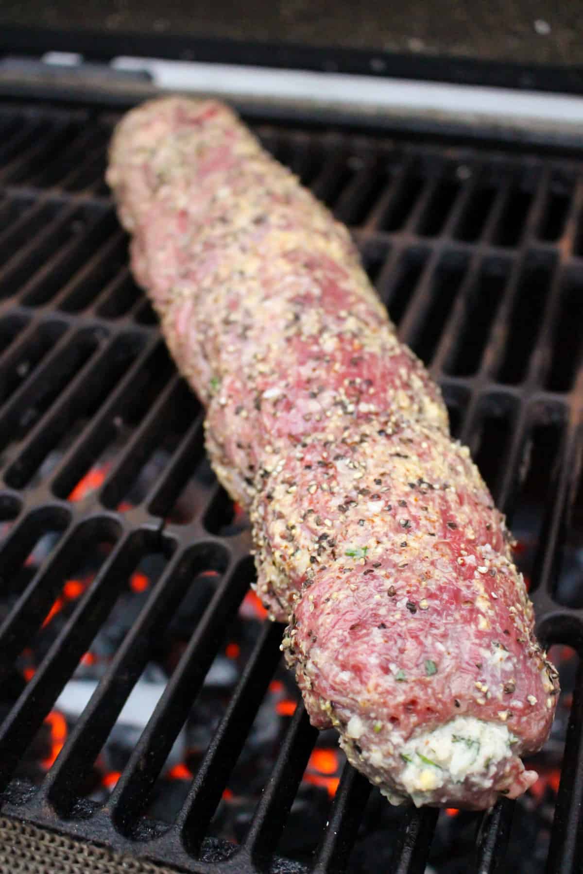 The seasoned, raw beef tenderloin hitting the grill.