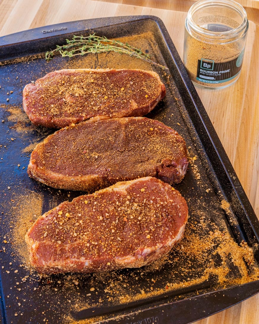 NY Strip Steaks get seasoned. 