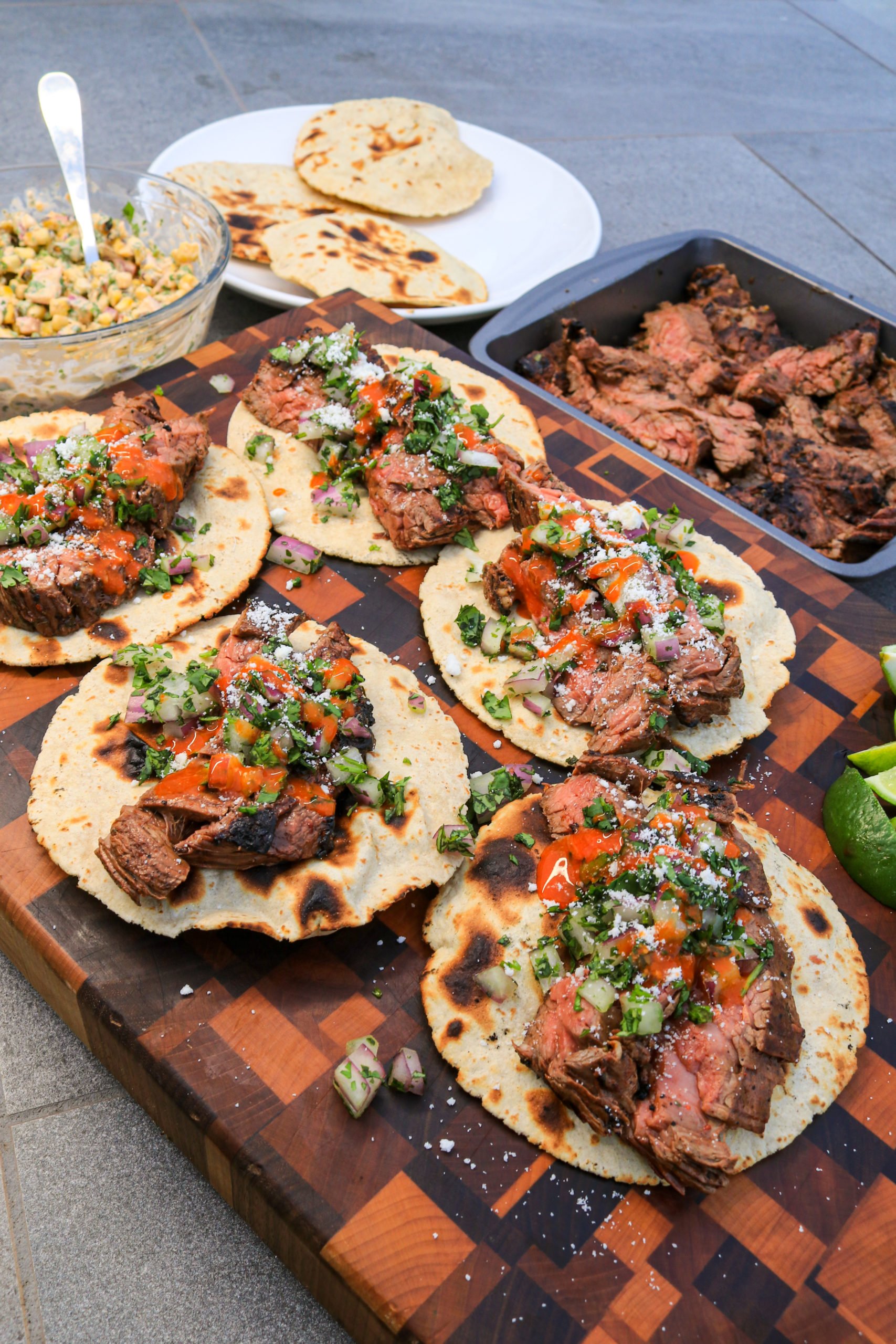 A shot of the steak tacos with all the corn salsa in the background.