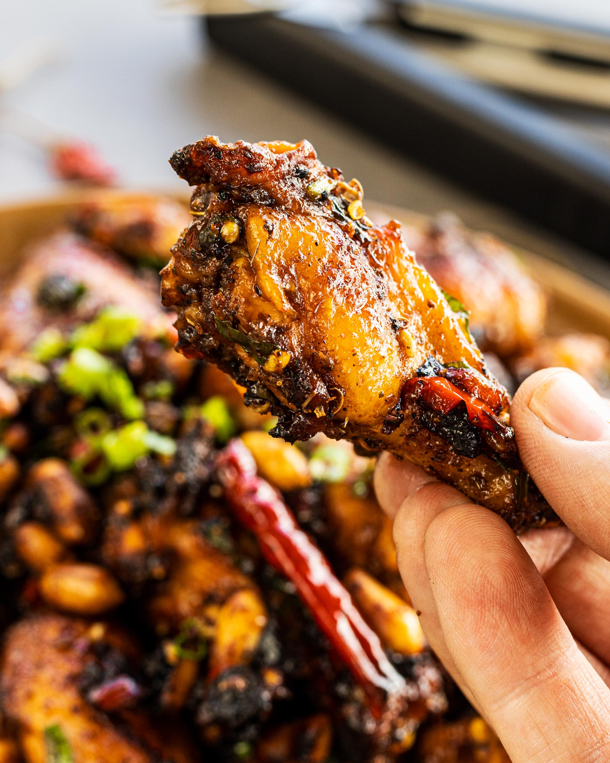 Grilled Kung Pao Chicken Wings a single wing held up close.