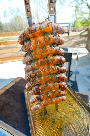 A vertical shot of finished chicken bacon ranch sausage skewers, displayed facing the camera on a cutting board