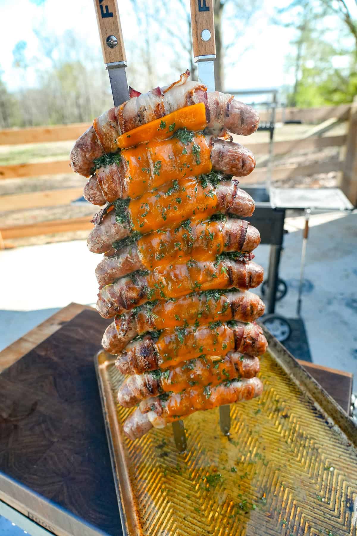 A vertical shot of finished chicken bacon ranch sausage skewers, displayed facing the camera on a cutting board