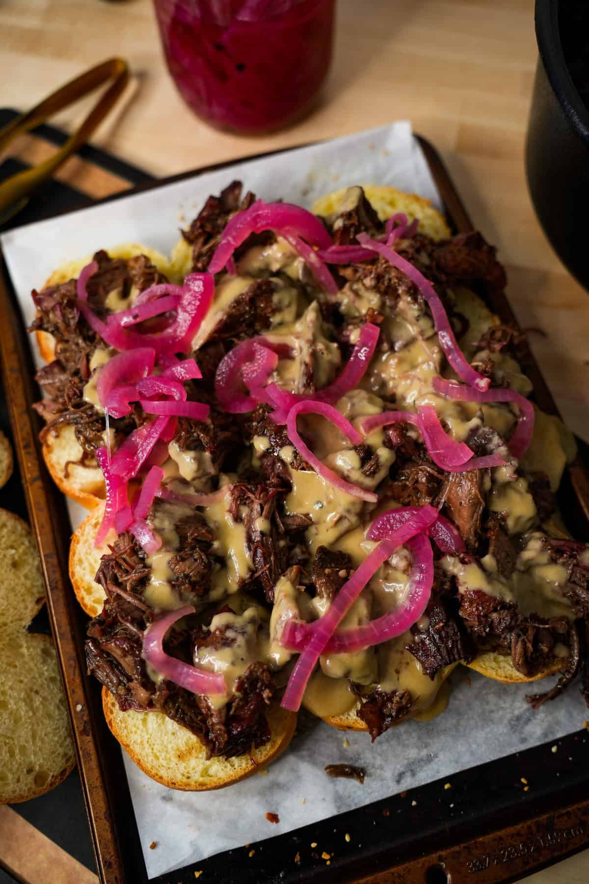 Guinness Pulled Beef Sliders in the assembly process with the beef, beer cheese and pickled red onions. 