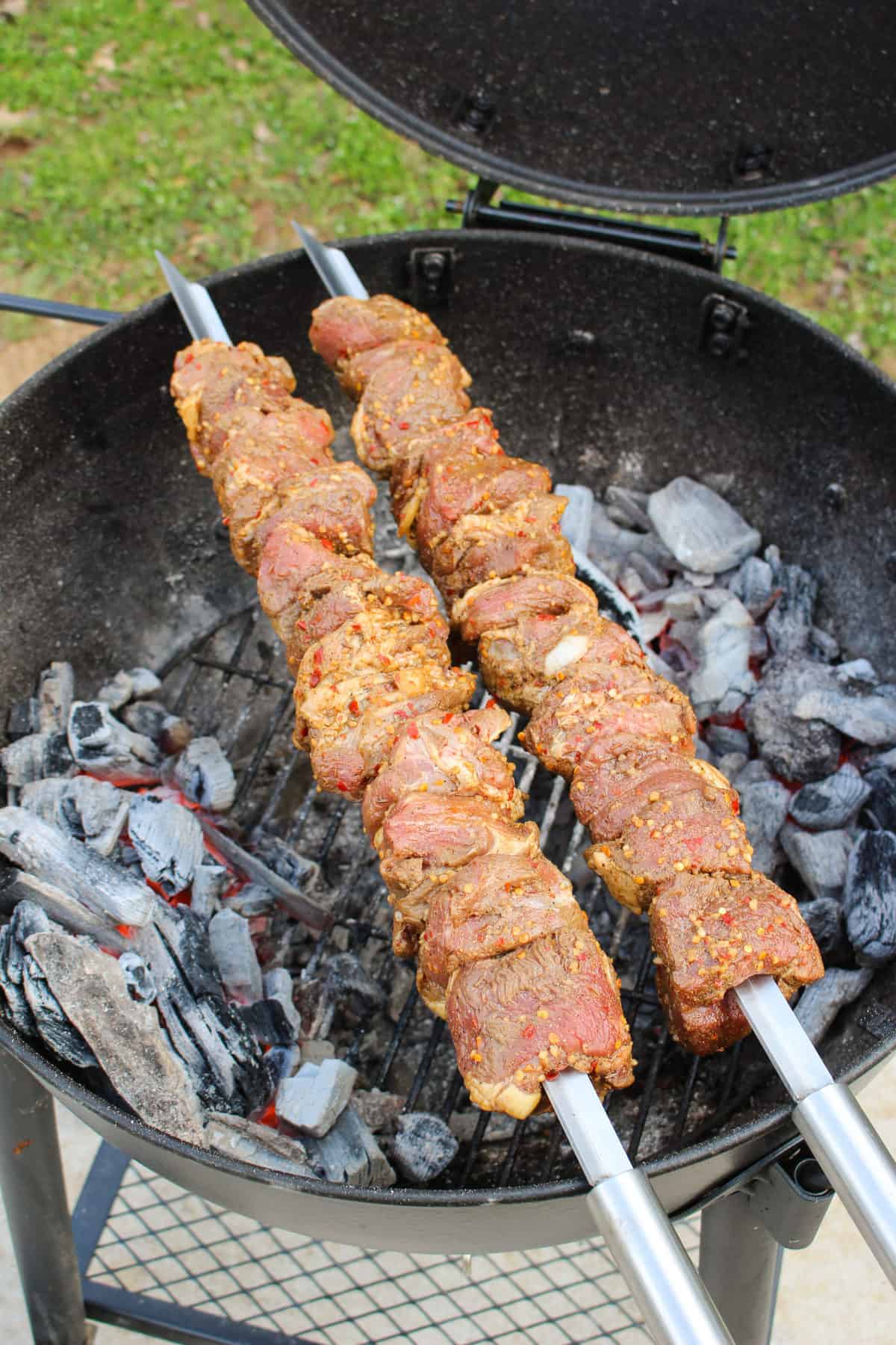 Spiced Lamb Kebabs with Mint Chimichurri getting placed over the coals on the grill. 