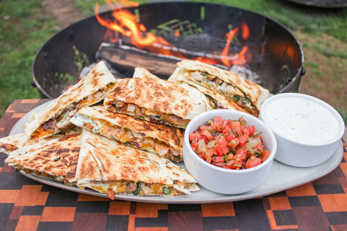 Chicken Bacon Ranch Quesadillas on a serving plate with the fire in the background.