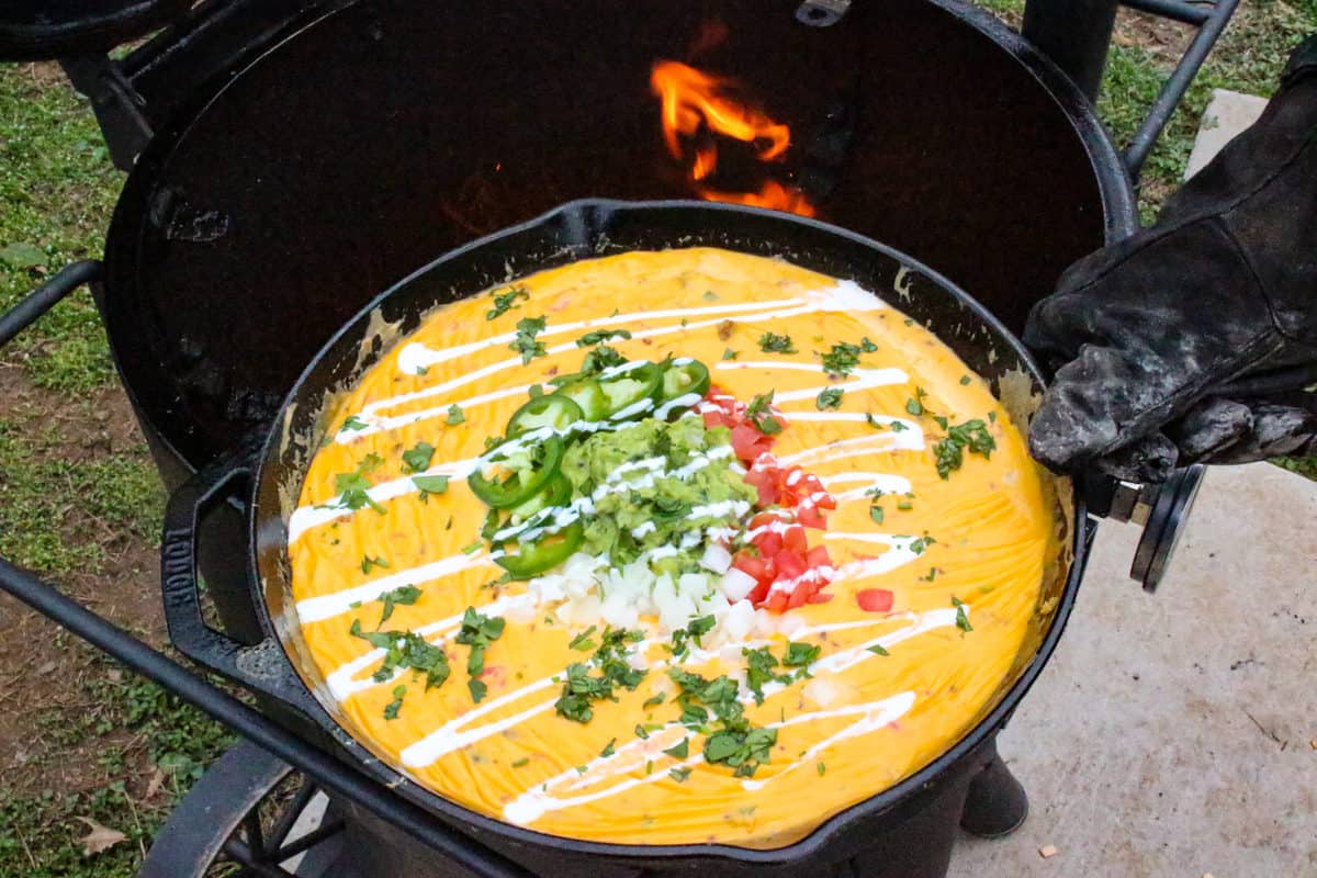 Queso sitting on the smoker with small flames in the background.