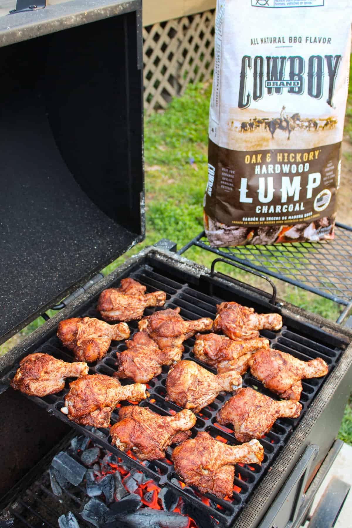 grilled butterflied chicken drumsticks on the grill with a bag of cowboy charcoal in the background
