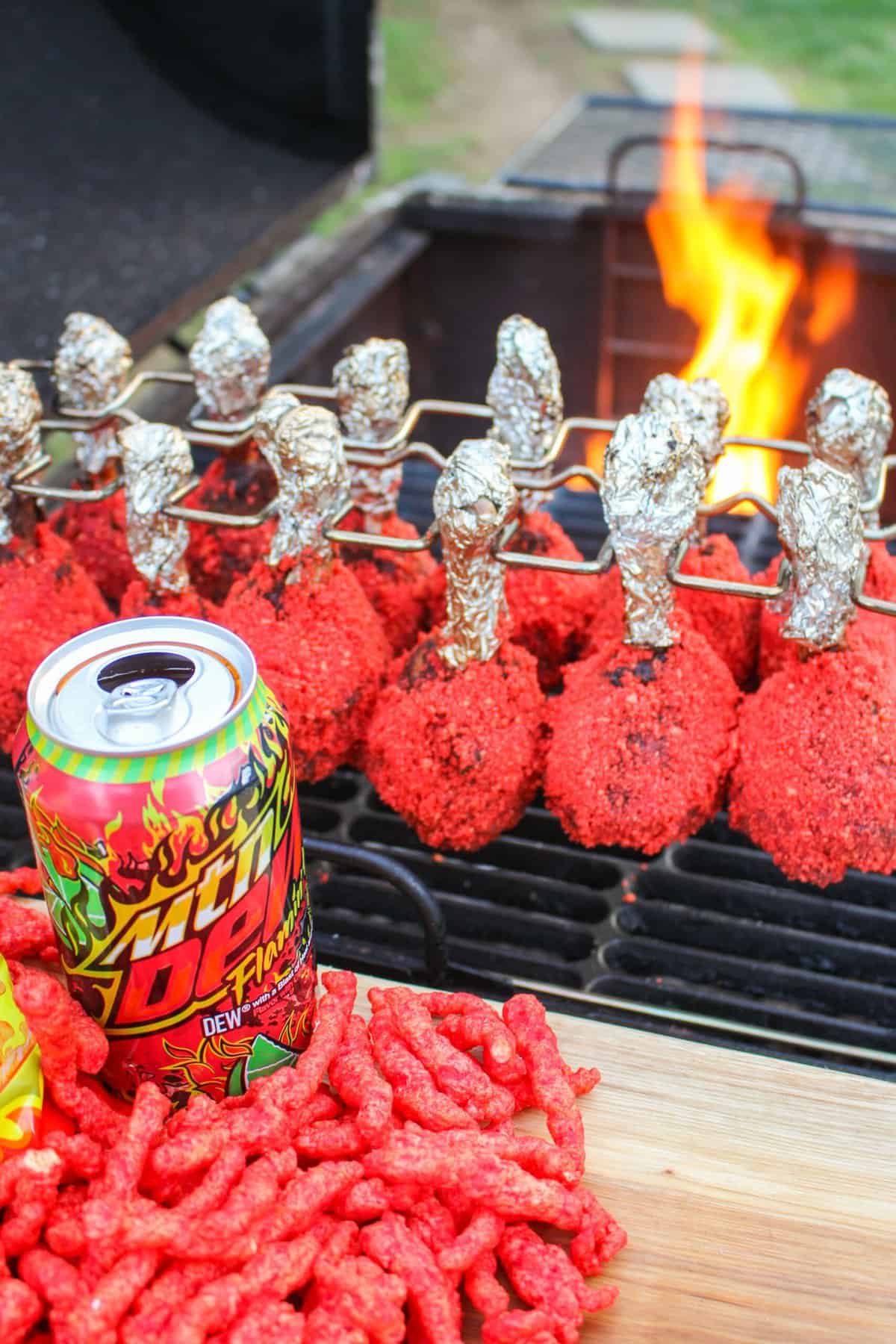 Flamin' Hot Chicken Lollipops sitting on the grill with fire in the background.