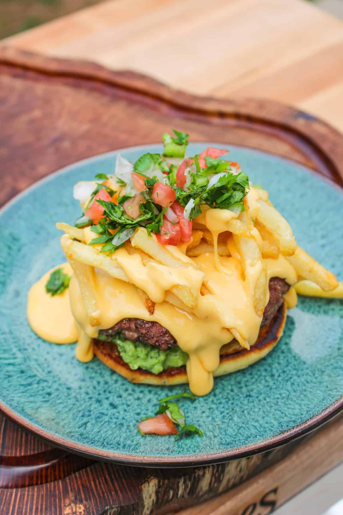 bottom burger bun topped with a burger patty, fries, and other toppings