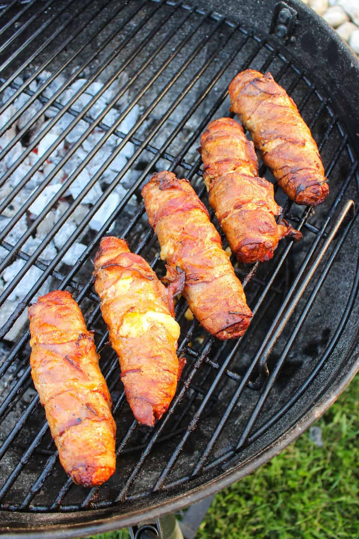 cooked bacon wrap hot dogs on a grill overhead