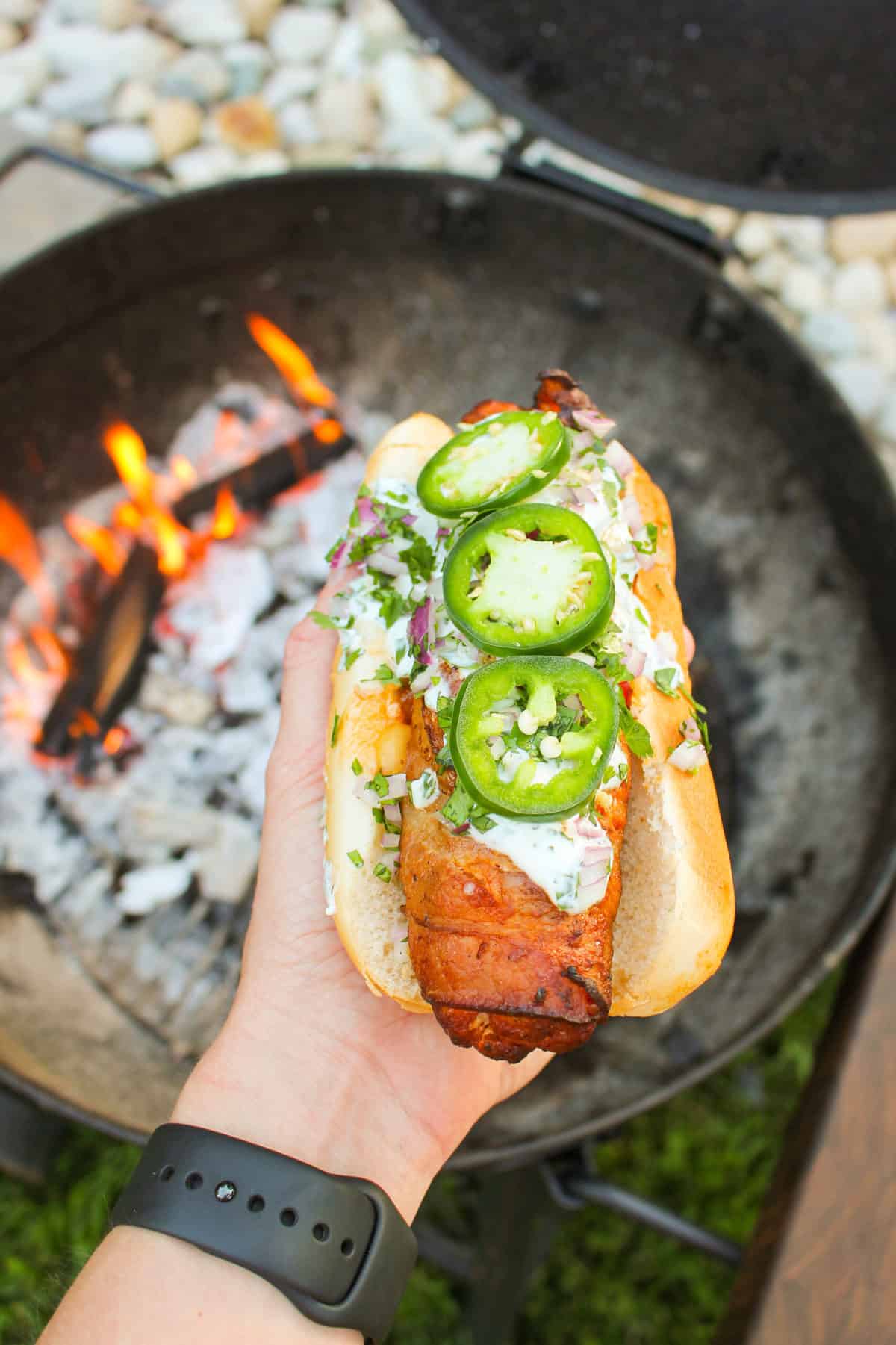 chorizo hot dog held over a fire pit
