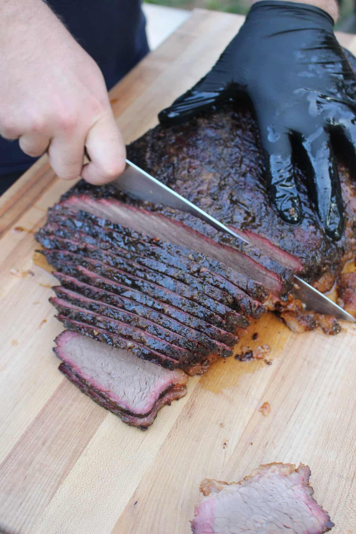 Derek slicing into the meat to finish out this smoked brisket recipe.