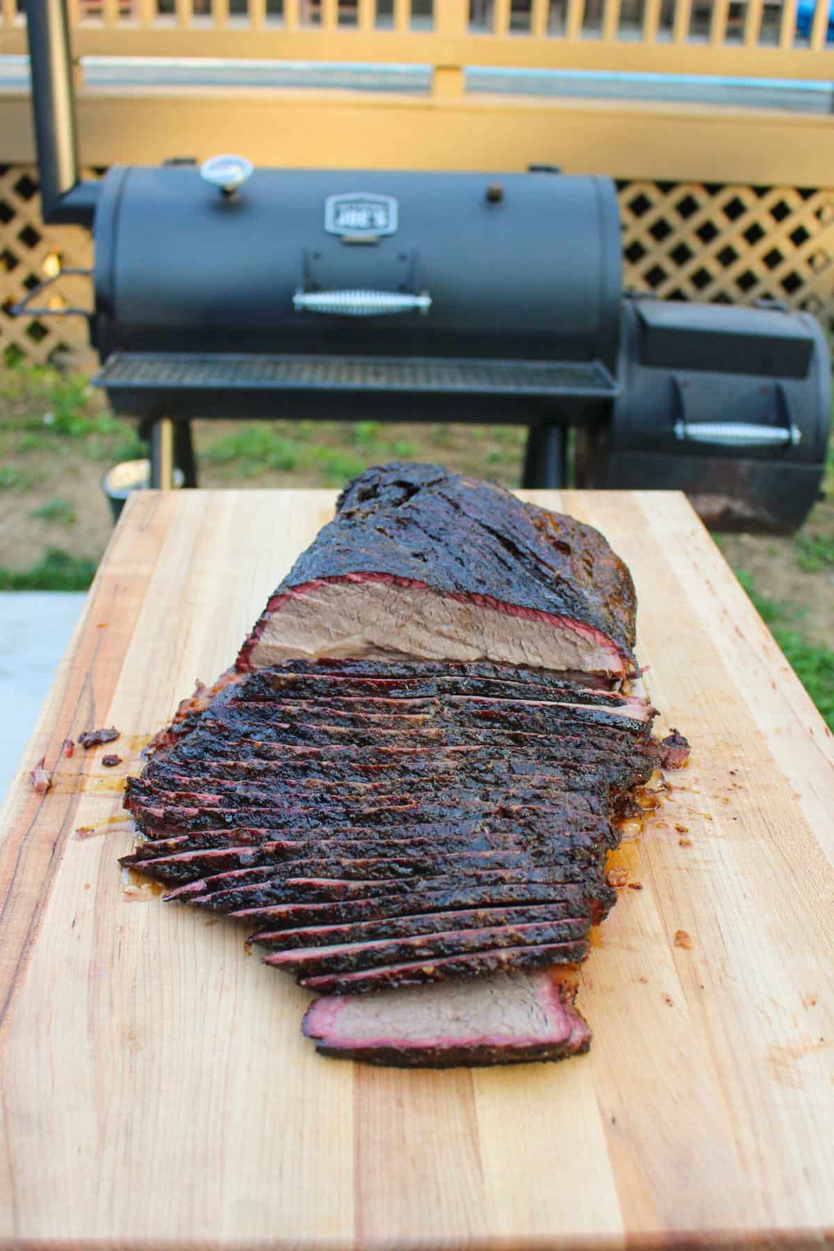 One final shot of the sliced brisket sitting on a cutting board in front of the smoker.