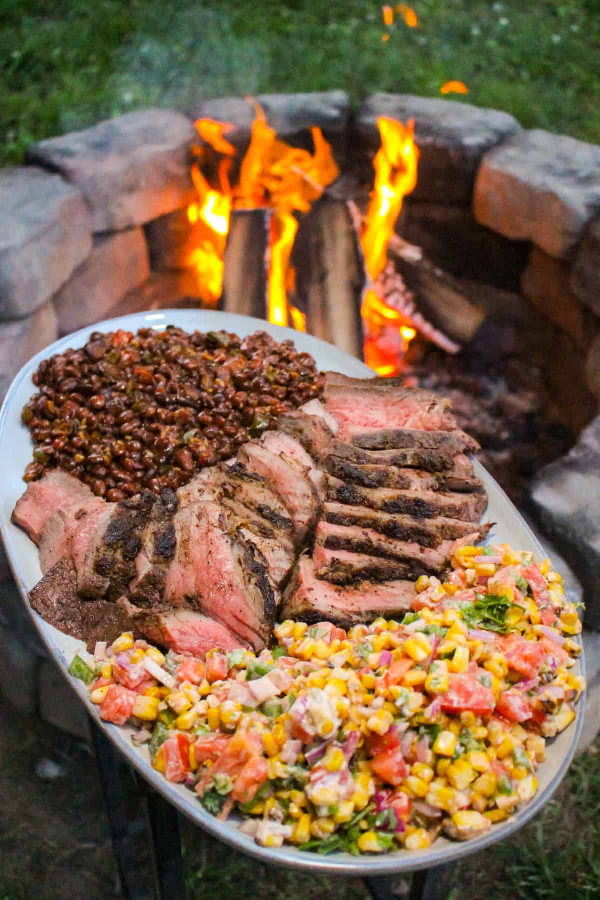 finished grilled tri-tip w/charred corn salsa on a plate with pinquito beans