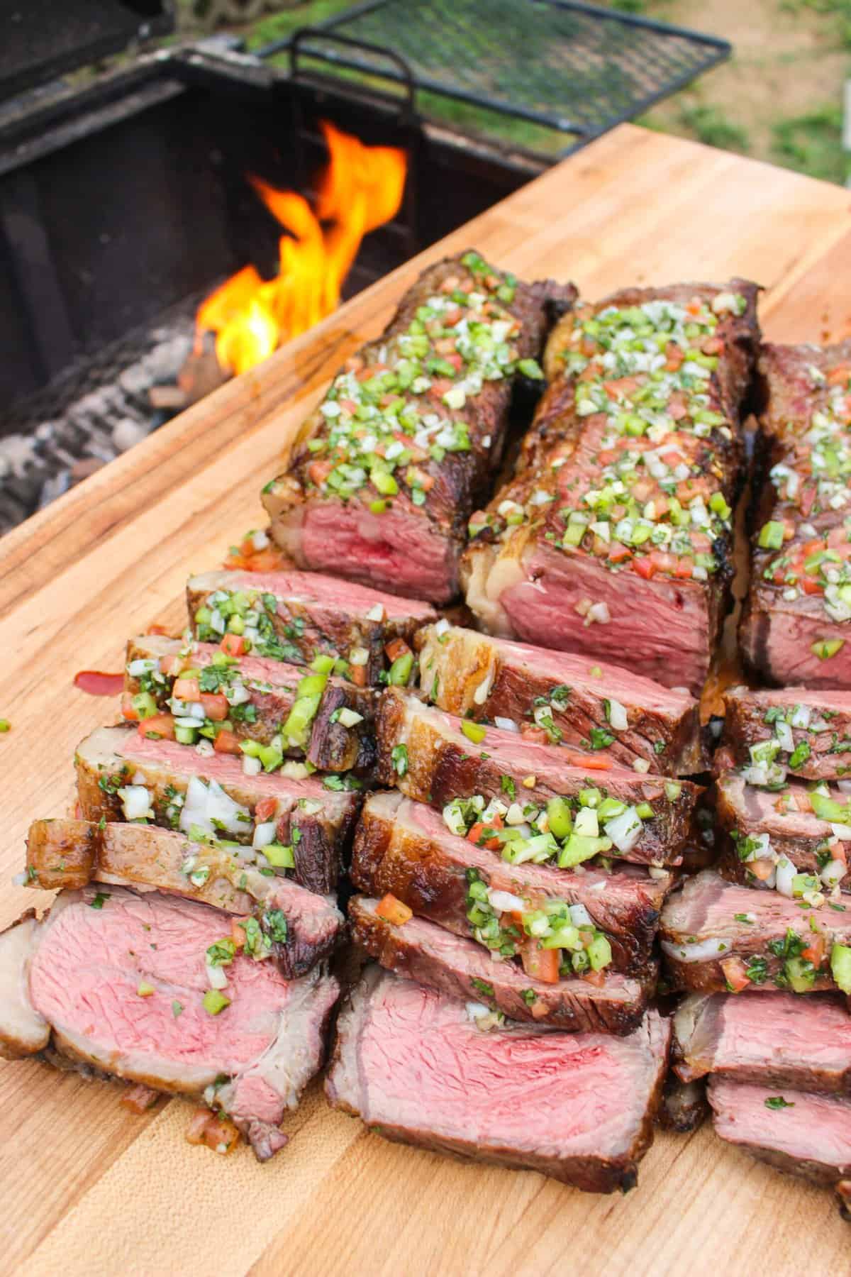 sliced strip steak skewers on a cutting board next to the grill