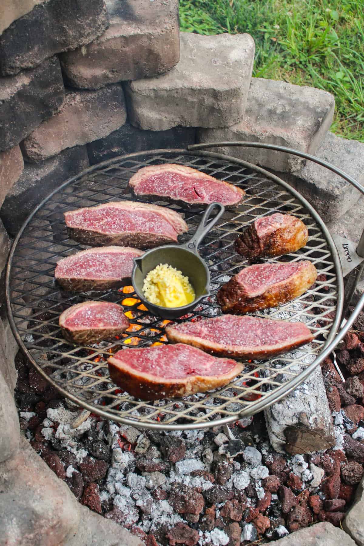 sliced picanha on the grill with a skillet of garlic butter