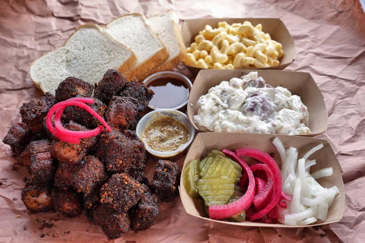 Pastrami Pork Belly Burnt Ends served with mac and cheese, slaw and sauces.