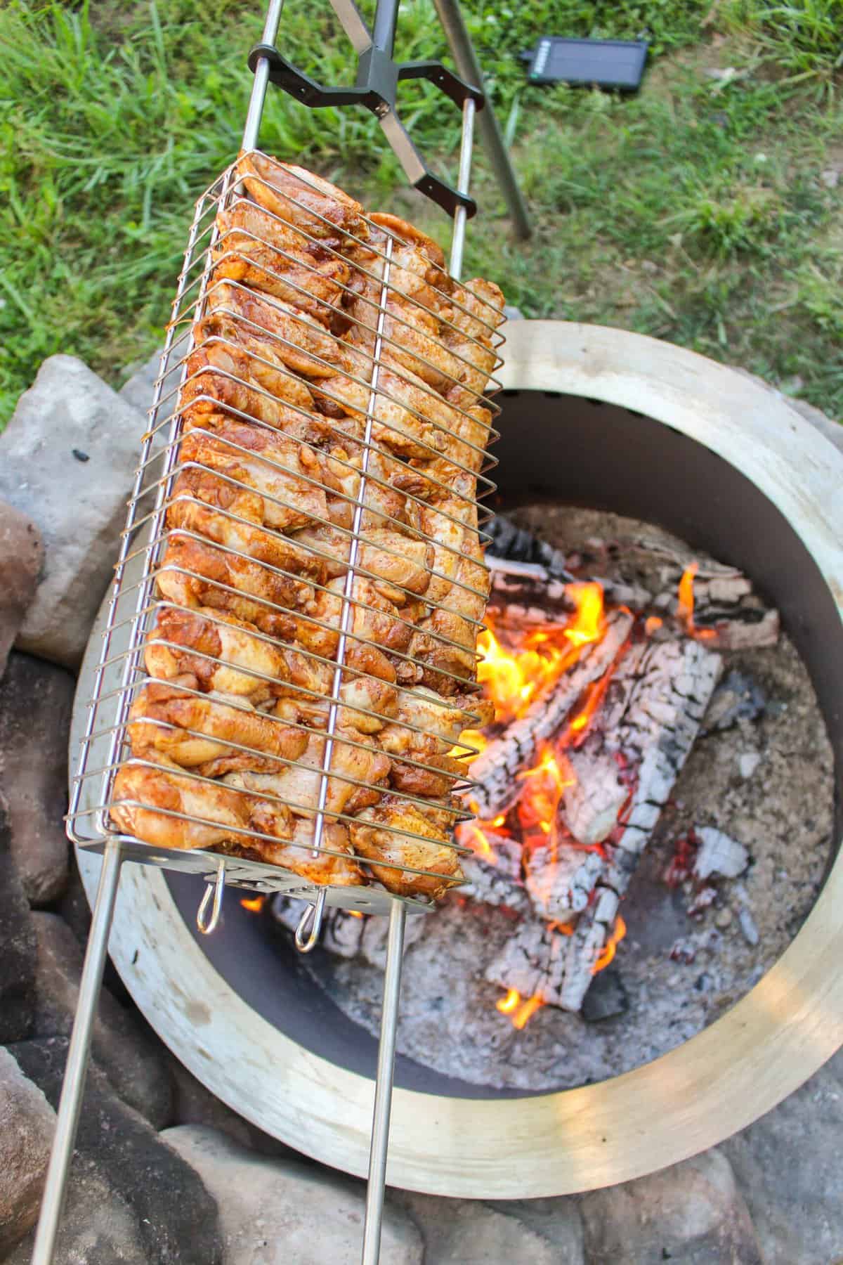 overhead of a rotisserie basket filled with chicken wings over a grill