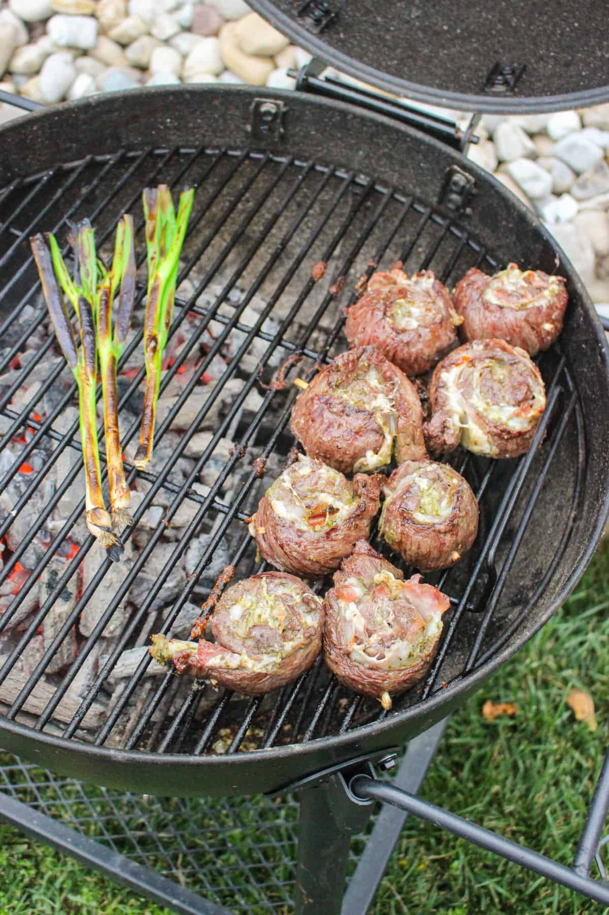 overhead of steak pinwheels and scallions on a grill