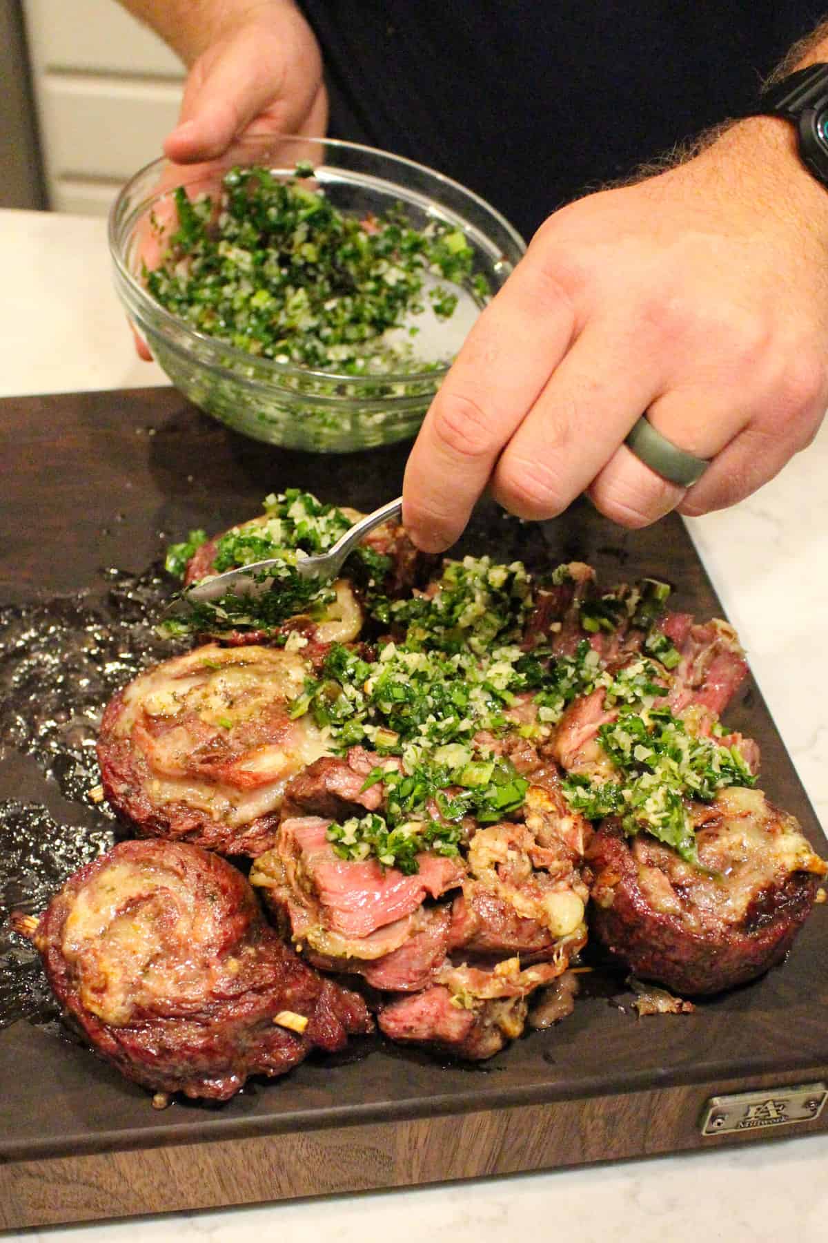 grilled steak pinwheels being topped with charred scallion gremolata