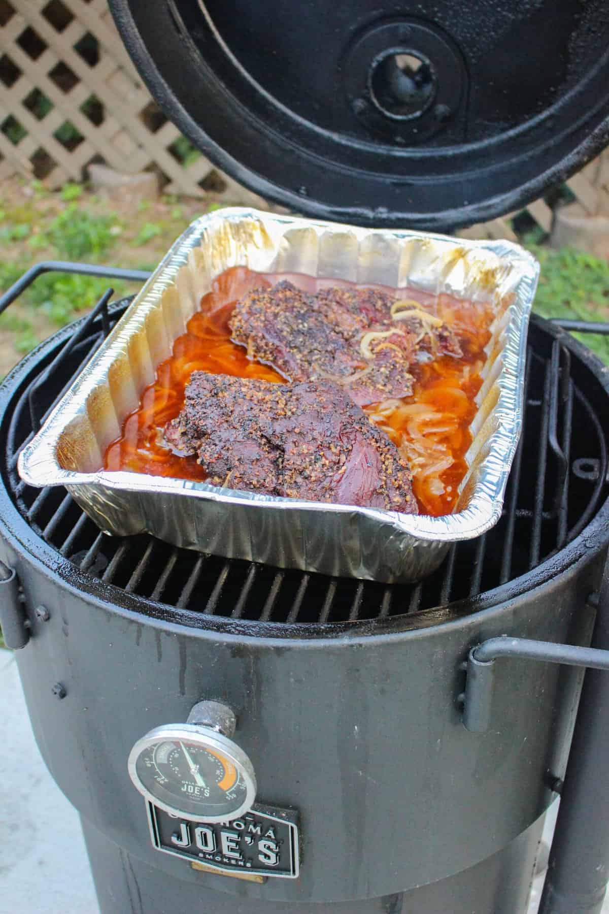 cooked chuck roasts in a foil bin on a smoker