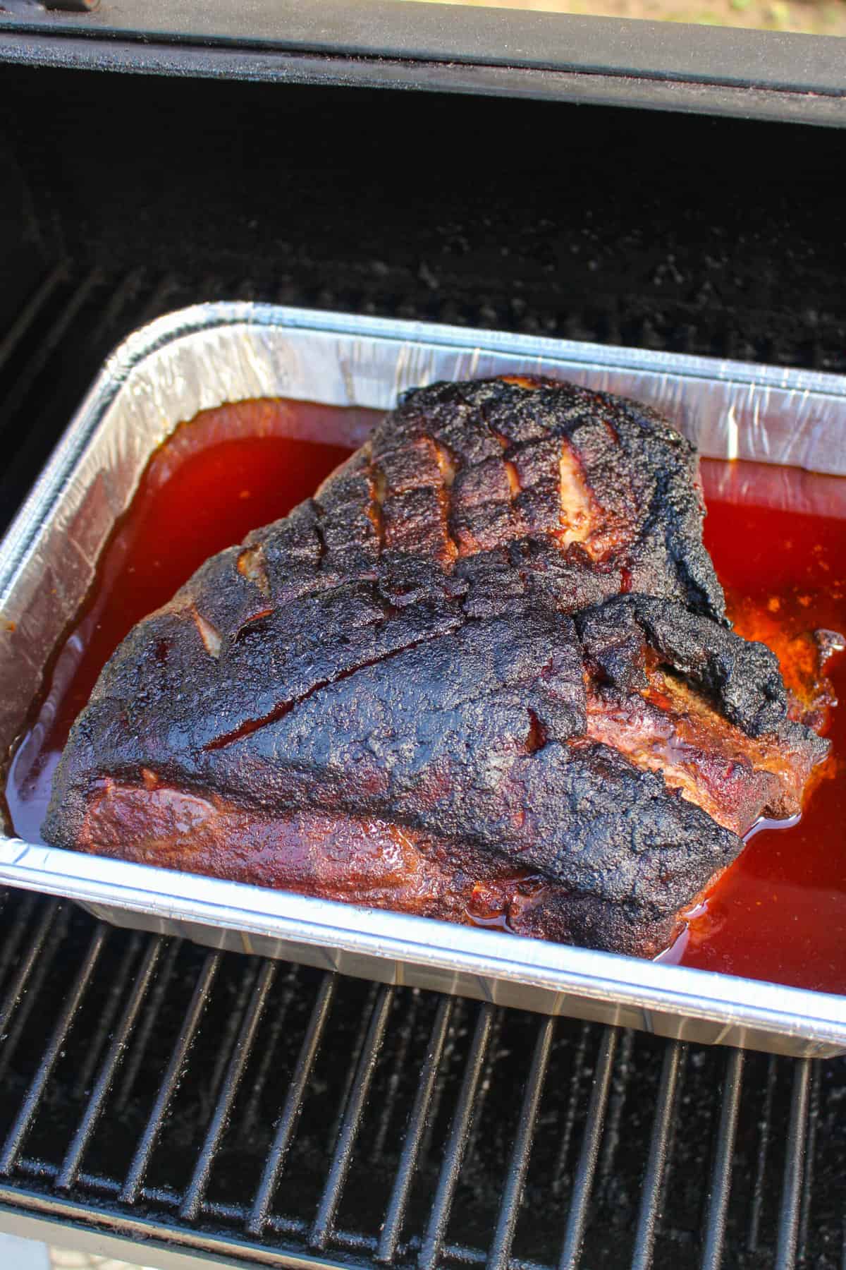 overhead of a smoked pork butt in a foil bin with liquid