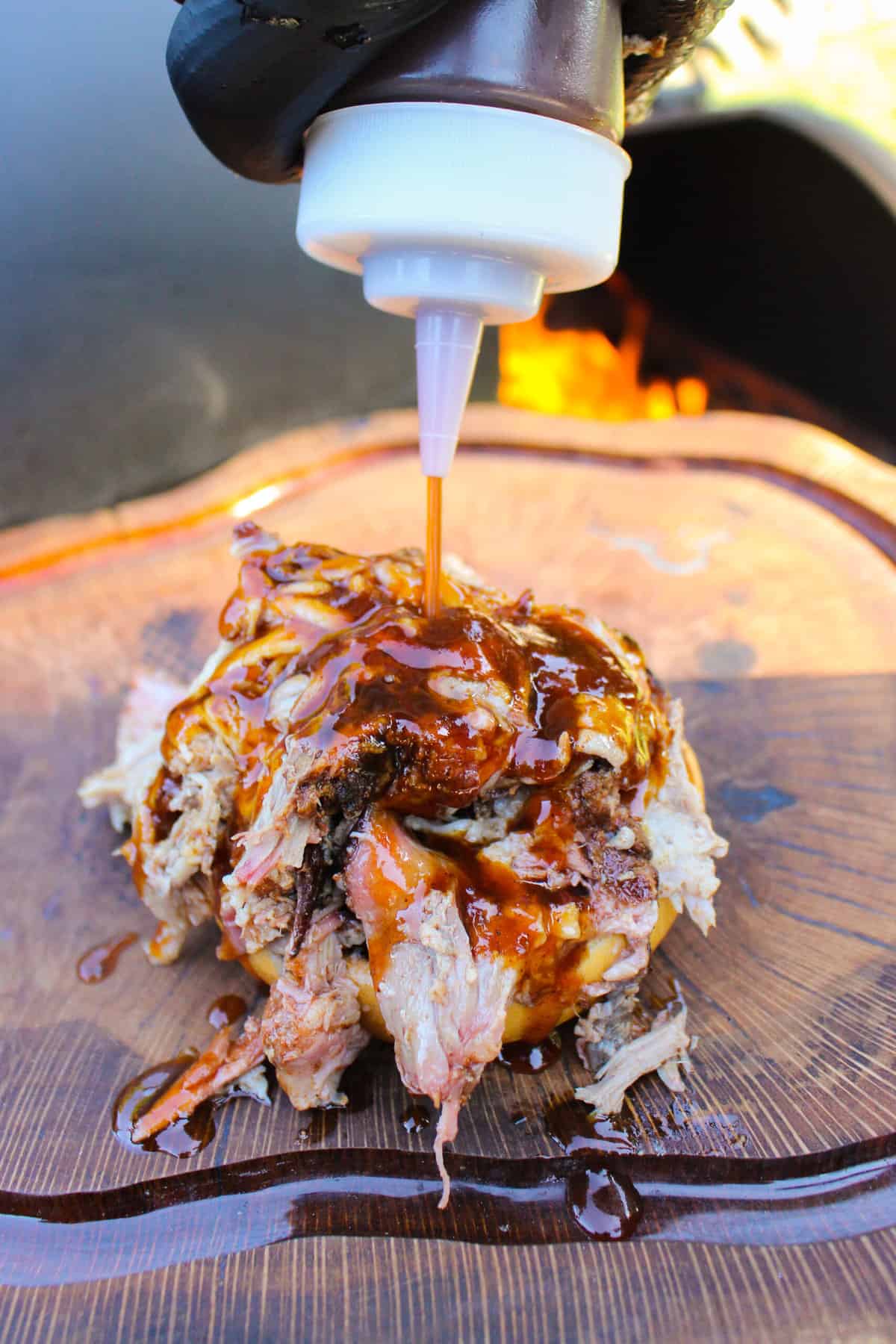chipotle bbq sauce being drizzled over a pulled pork sandwich