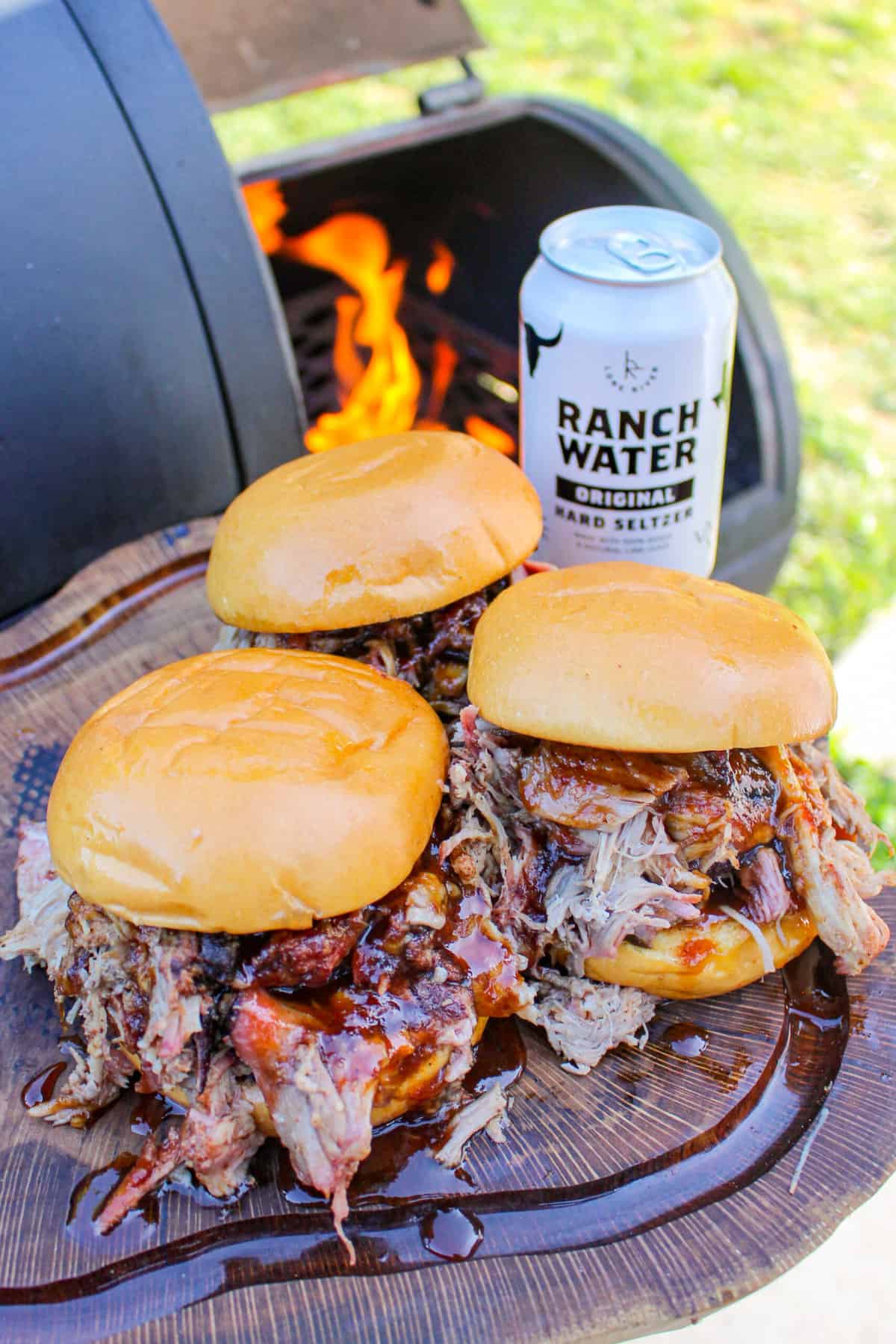 overhead of three pork sandwiches next to a smoker