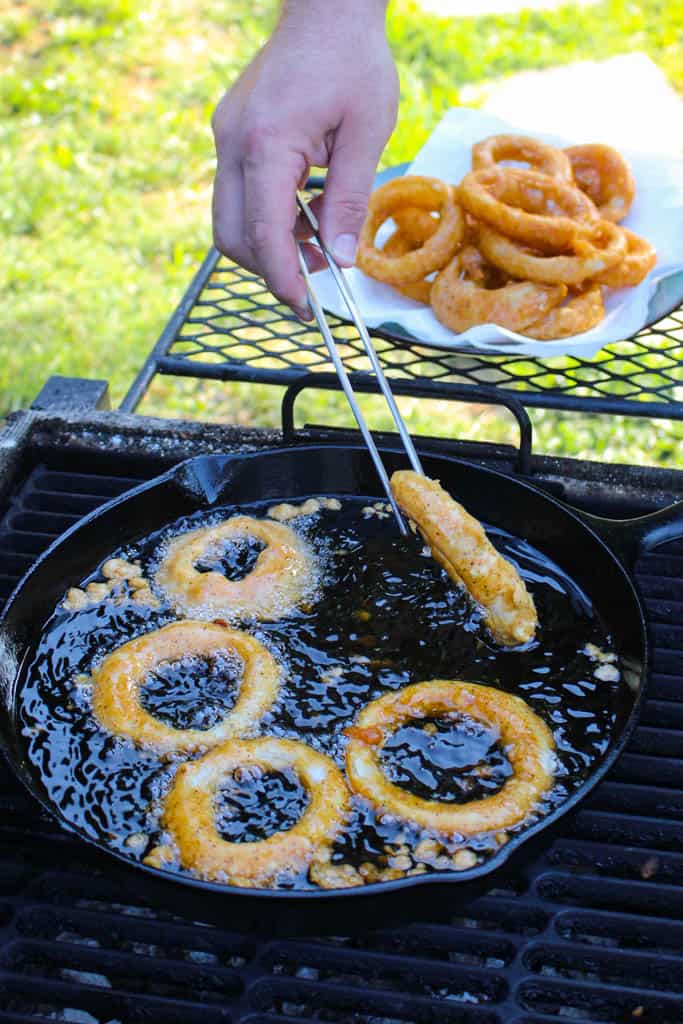 breaded onion rings in hot oil being flipped over