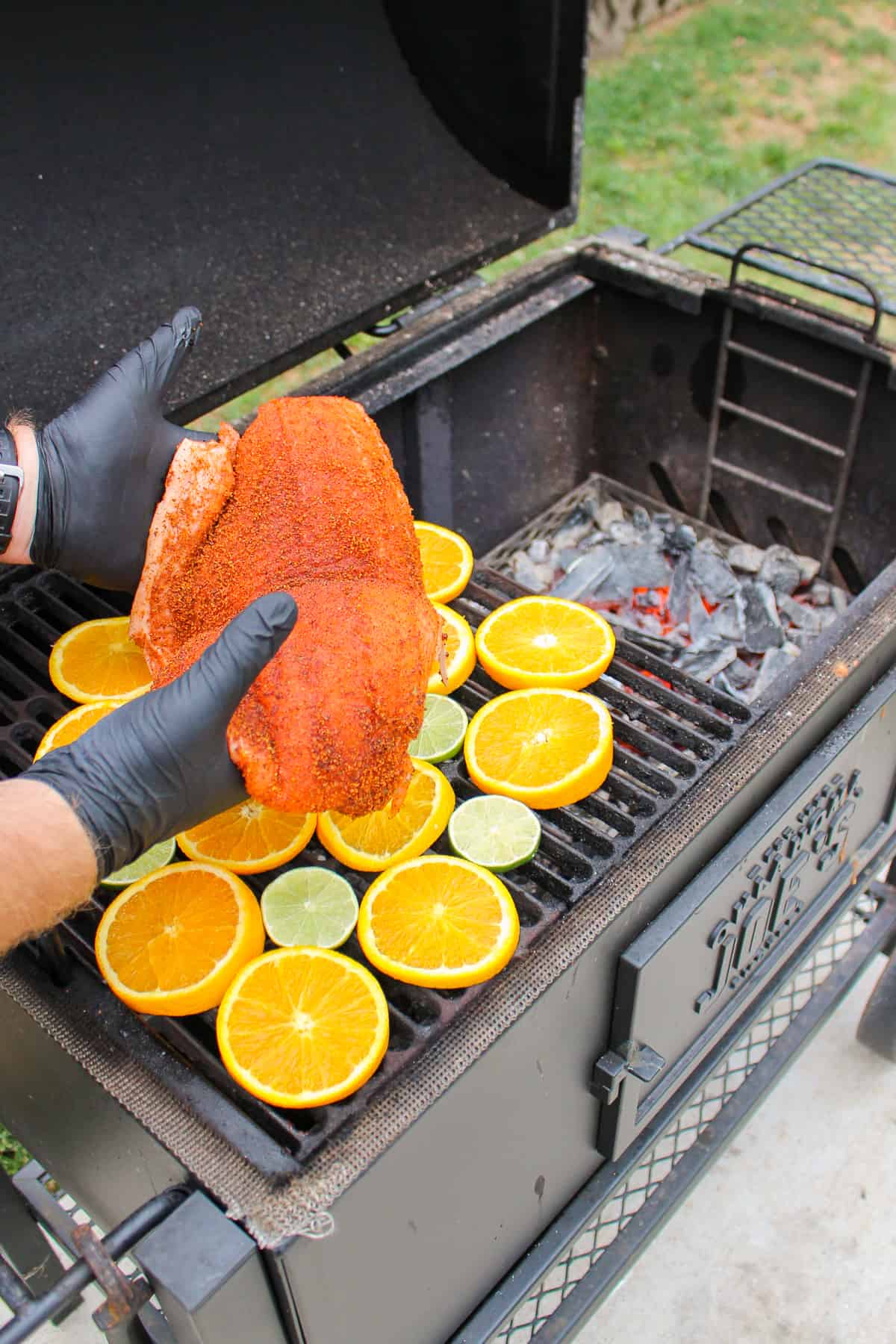 salmon being placed onto a grill full of citrus fruit