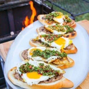 side view of buns layered with ground sausage, egg, and chimichurri on a plate