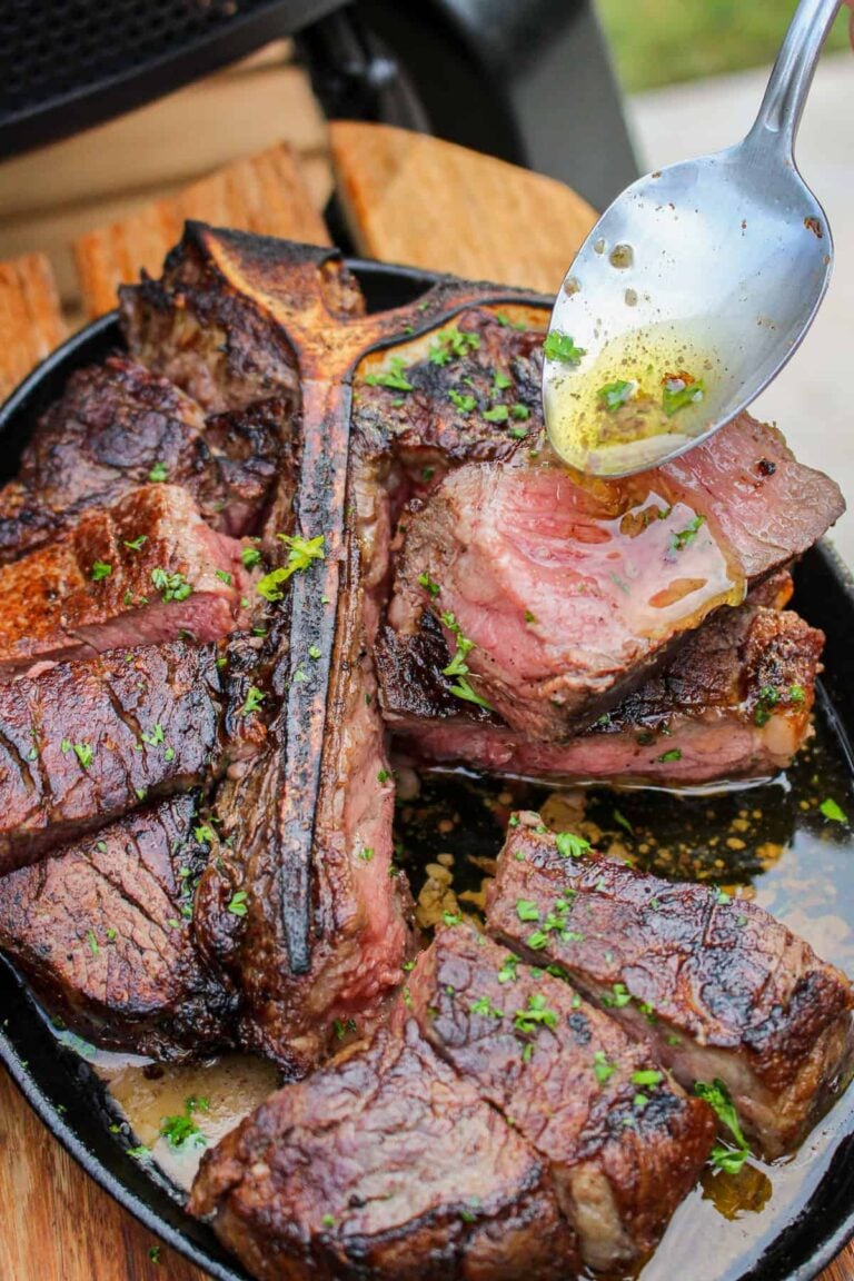 closeup of a plate of steak being drizzled with garlic butter