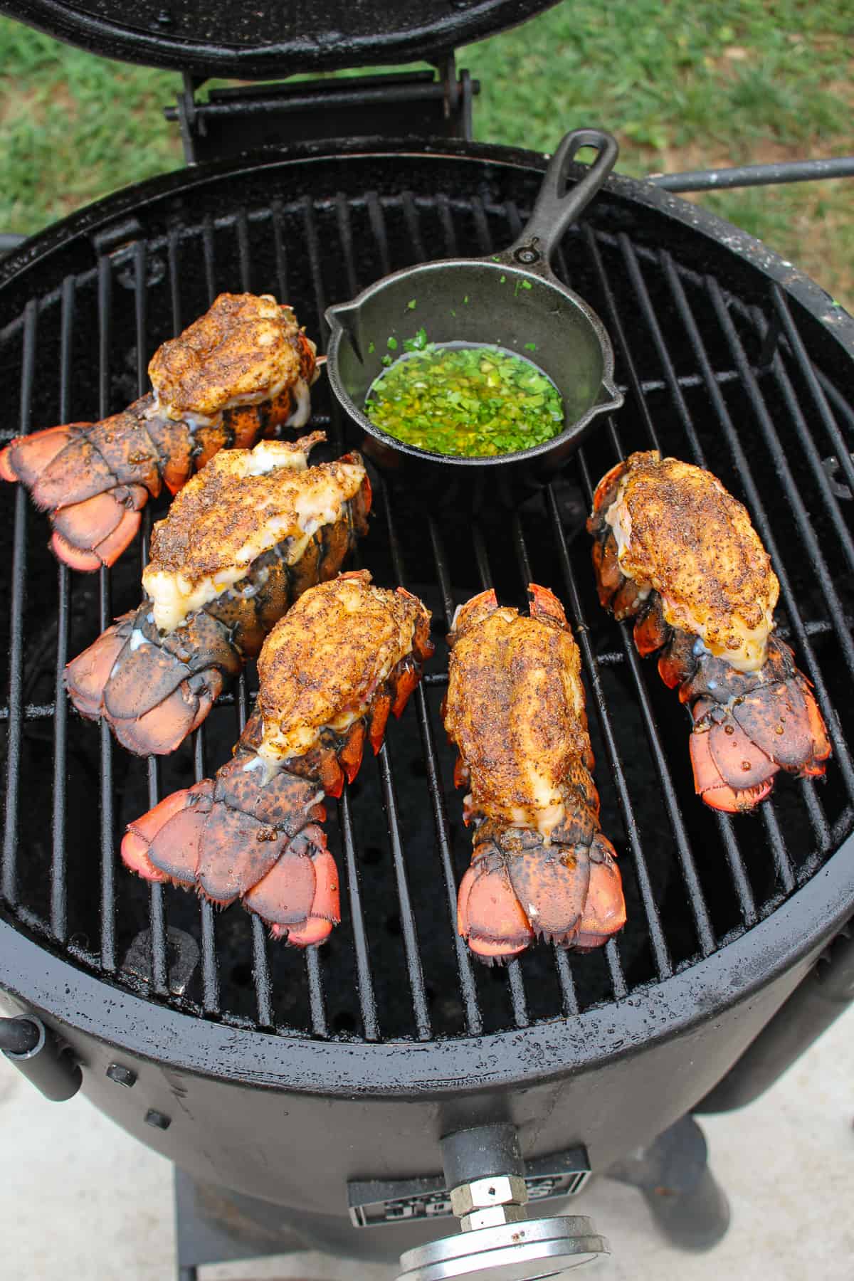 overhead of lobster on a smoker with a basting skillet full of garlic butter