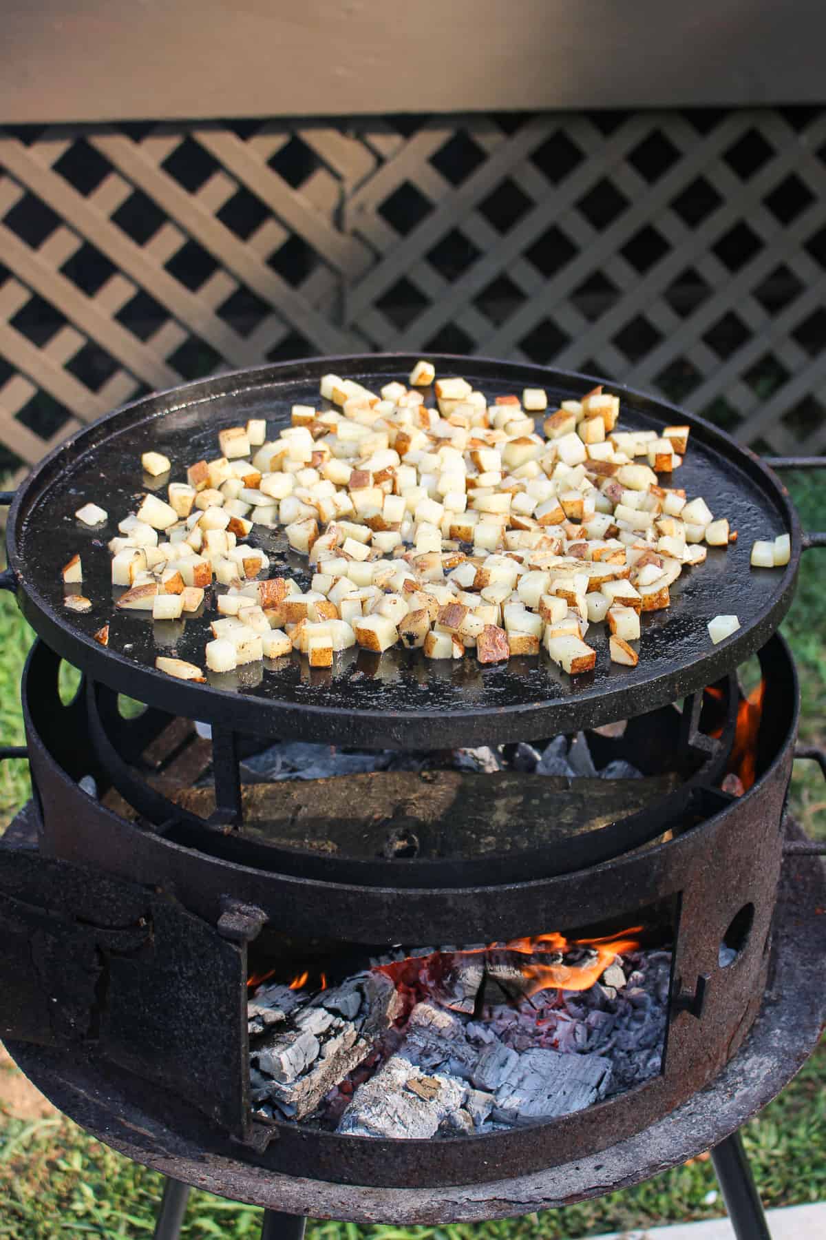 diced potatoes being cooked on a plancha on the grill