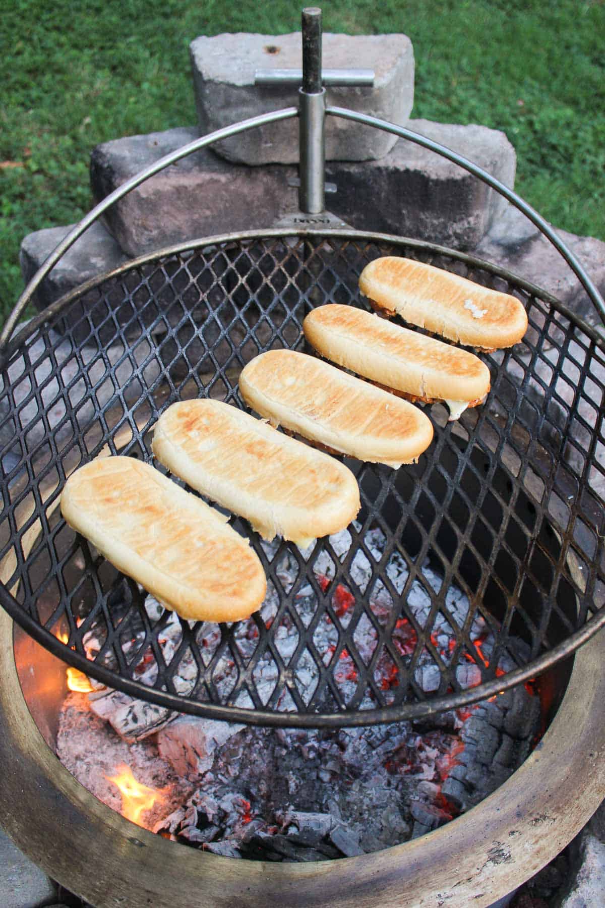 cheese stuffed choripan bottom buns being cooked face down on a grill grate