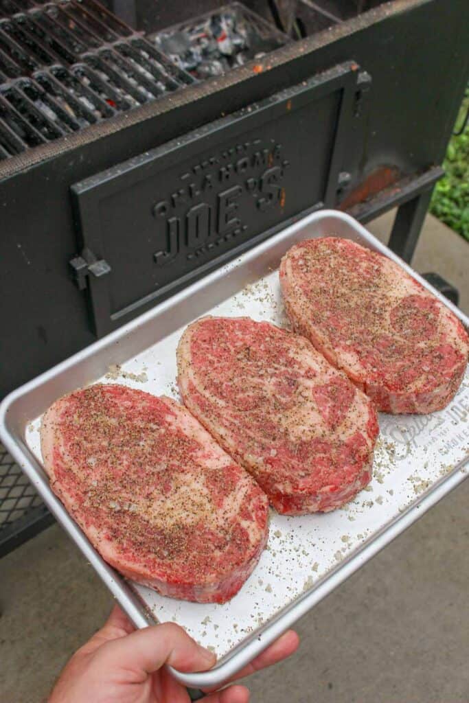 Seasoned steaks on the smoker.