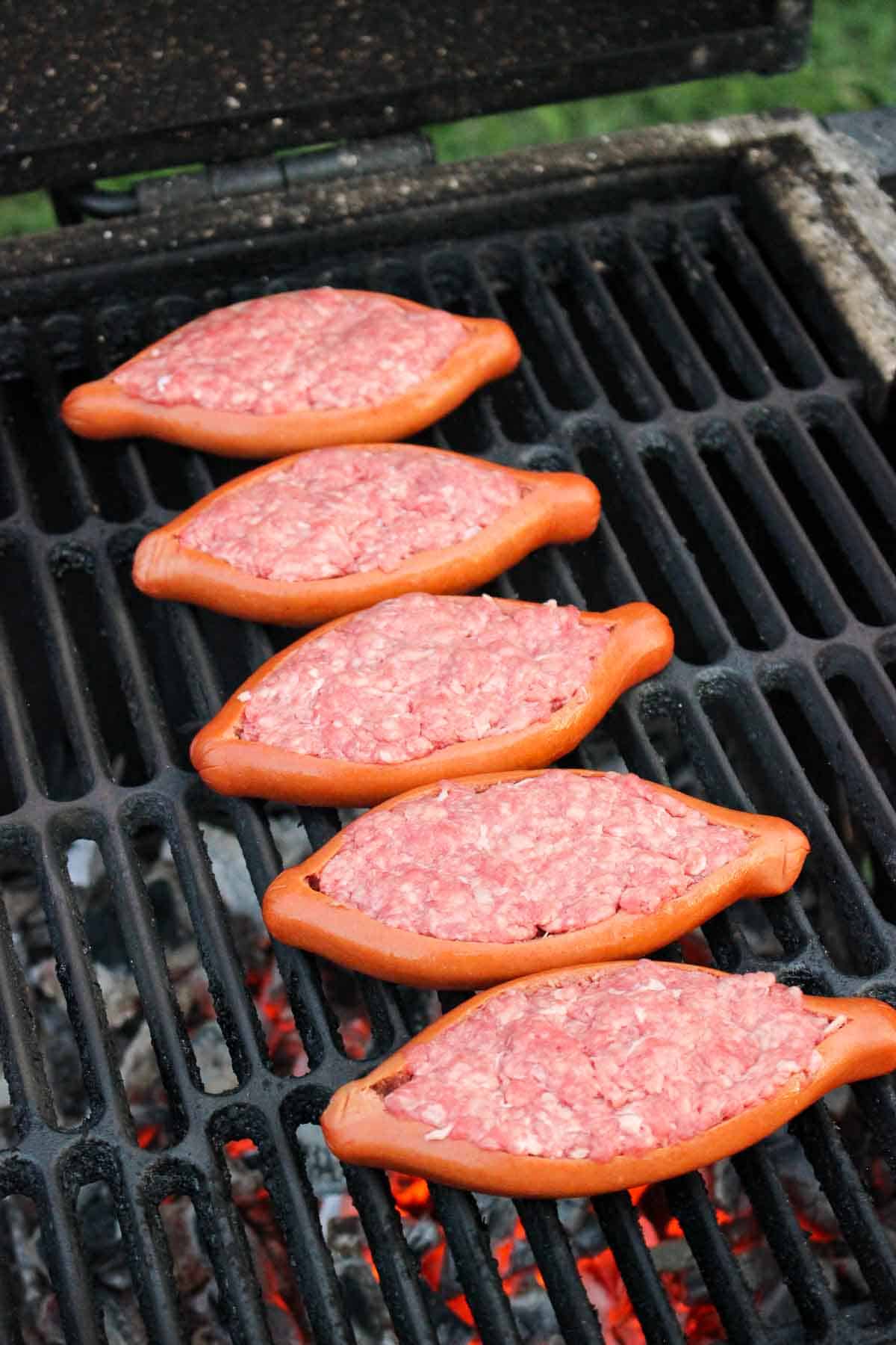 closeup of beef stuffed hot dogs lined on a grill