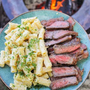 overhead of a plate piled with cheesy pasta and sliced strip steak