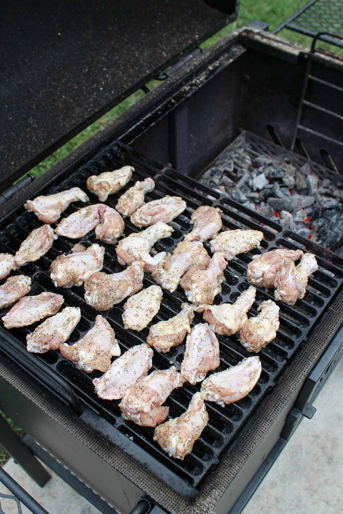 uncooked chicken wings lined on a grill grate