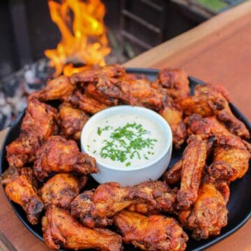 overhead of a plate of smoked double fried wings next to a grill