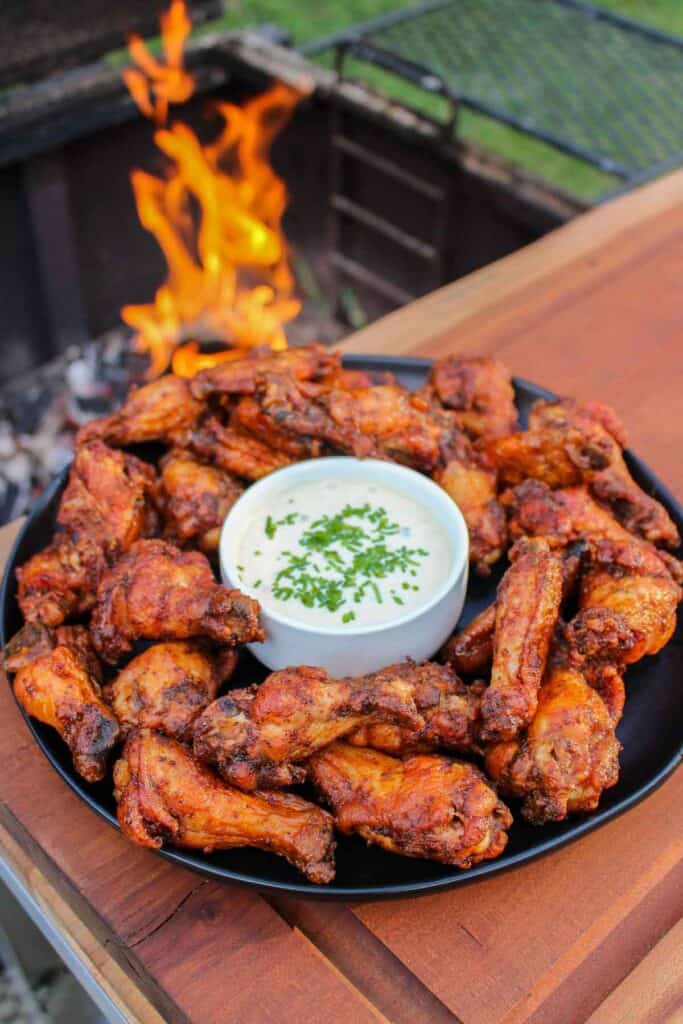 overhead of a plate of smoked double fried wings next to a grill