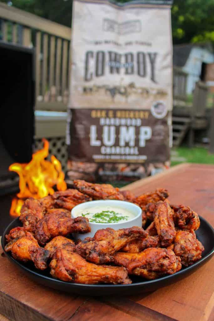a plate of chicken wings in front of a back of cowboy charcoal