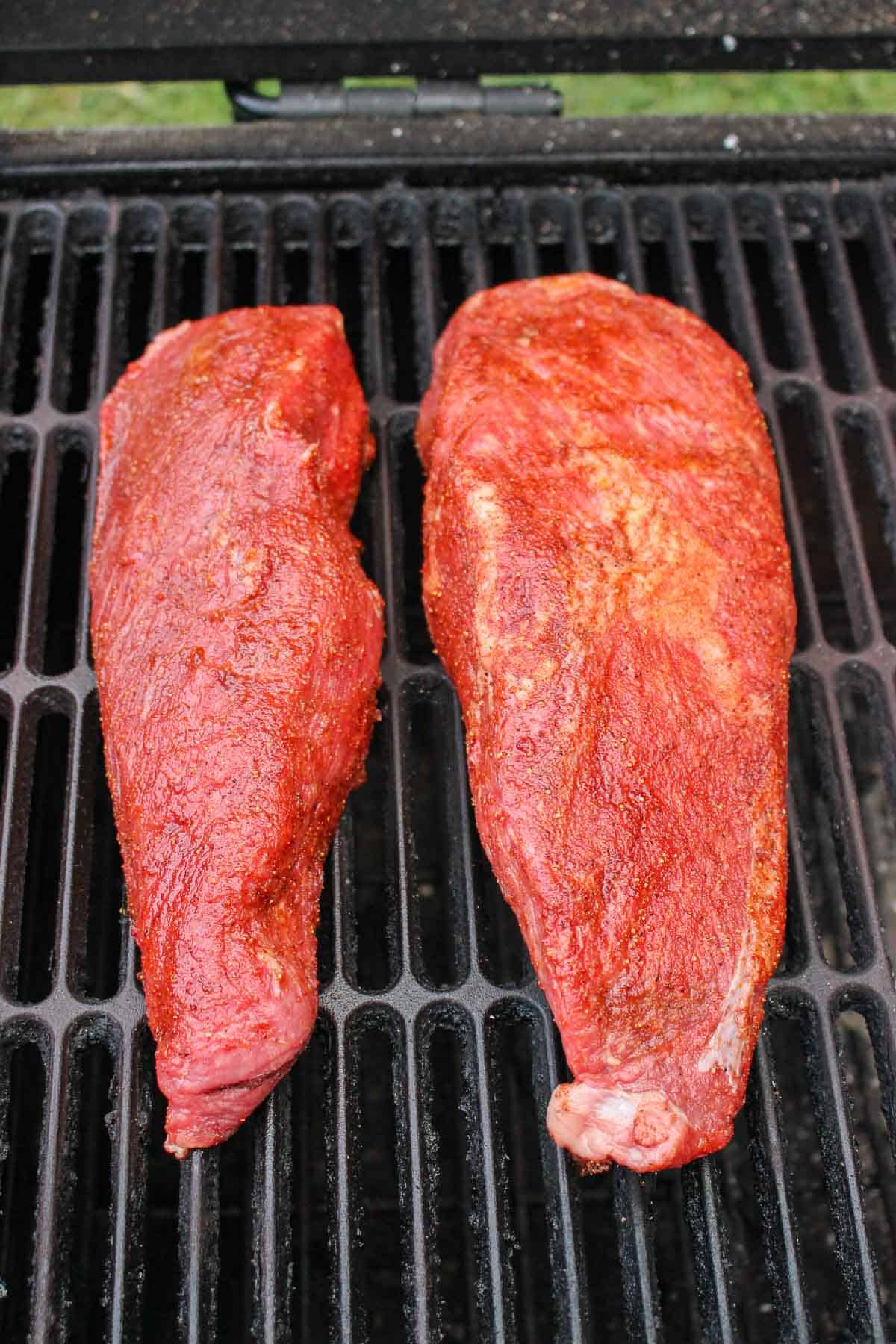 two seasoned tri tips on a grill