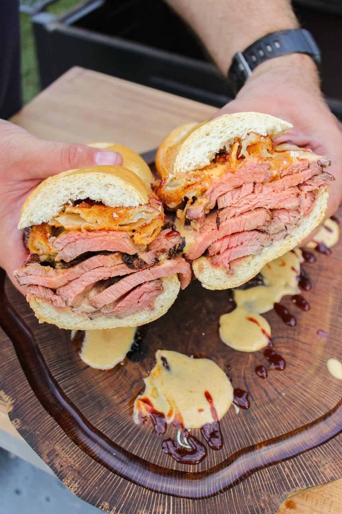 two halves of a steak sandwich held over a cutting board