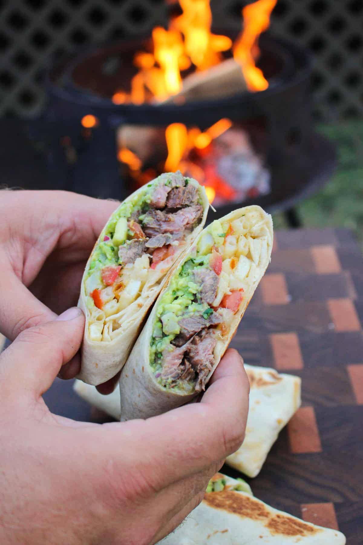 two halves of a california burrito held over a fire