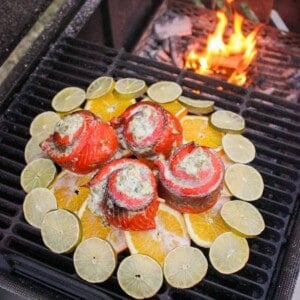 green chili salmon pinwheels on a citrus plank on the grill next to a fire